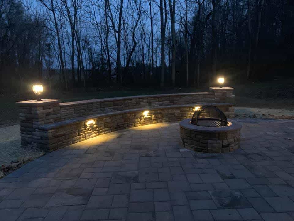 Picture of patio with small wall with seating and firepit, night